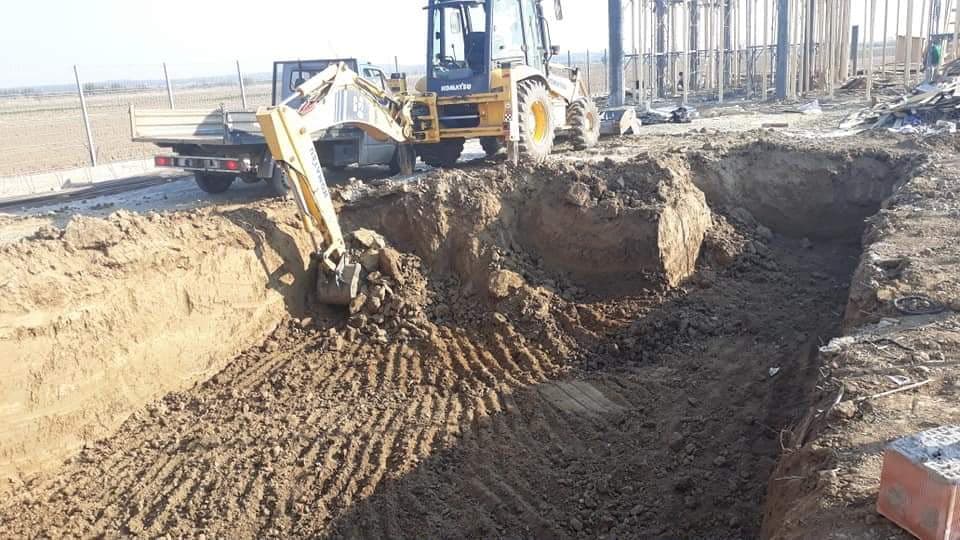 Buldoexcavator Komatsu săpând groapa de fundație pentru o construcție nouă, cu pereți verticali